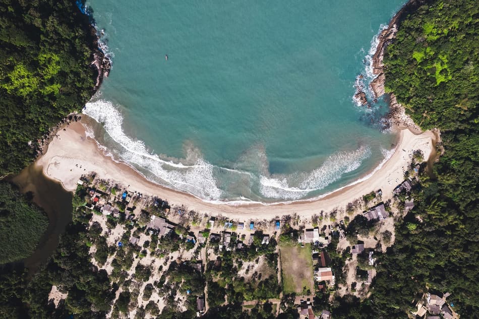 Vista aérea de uma enseada com praia e mata no litoral